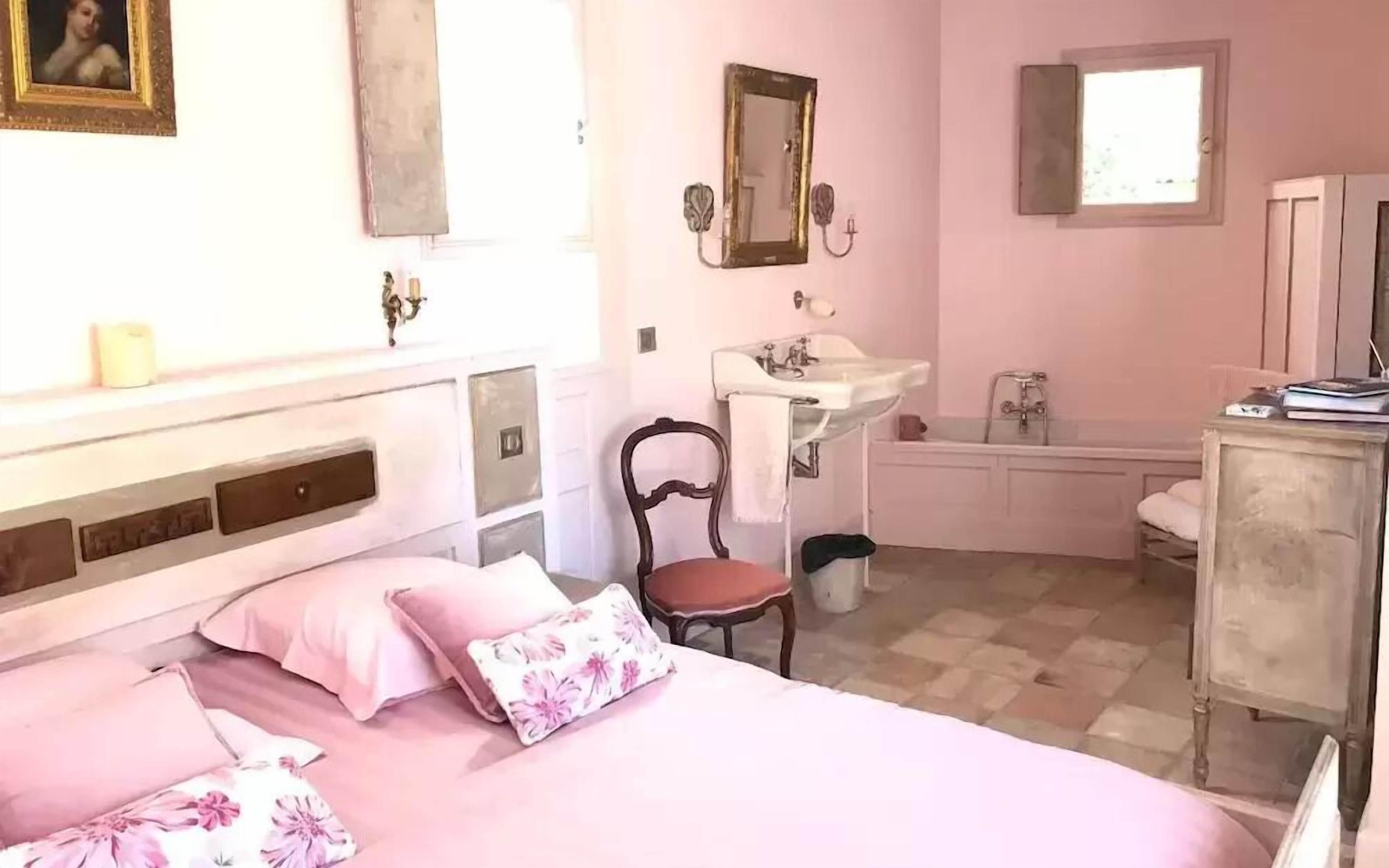 Egy hálószoba, amelyben található egy ágy, egy szék, egy komód, egy ablak, valamint egy fürdőszoba mosdókagylóval és fürdőkáddal.