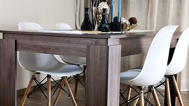 A dining area with a wooden table, white chairs, and a decorative vase with candles. - The Bridge-House Apartment (Nicosia)