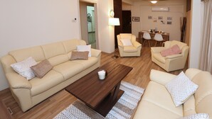 A living room with a beige sofa, a wooden coffee table, and two armchairs. - The Bridge-House Apartment (Nicosia)