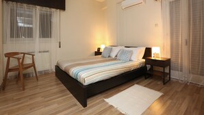 A bedroom with a bed, bedside tables, a chair, and a window with curtains. - The Bridge-House Apartment (Nicosia)