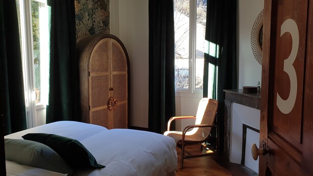 A bedroom with a bed, a chair, a wardrobe, and a large number on the wall.