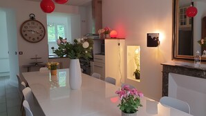 A modern dining area with a white table, chairs, and a clock on the wall.