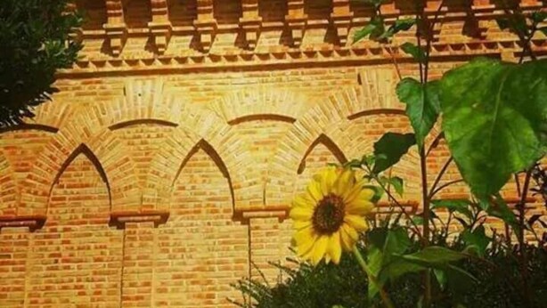 Un edificio de ladrillo con ventanas de arco y una pequeña torre.