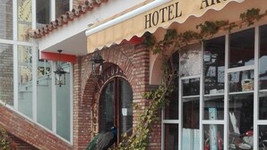 Un hotel llamado "ARCO" con fachada de ladrillo, un patio con baldosas y asientos al aire libre.