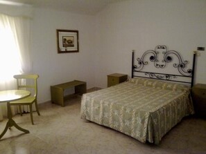 Ein Schlafzimmer mit einem Bett, einem Sessel, einem kleinen Tisch und einer Bank.