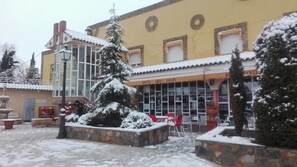 Un hotel con fachada cubierta de nieve, zona de estar exterior y entrada visible.