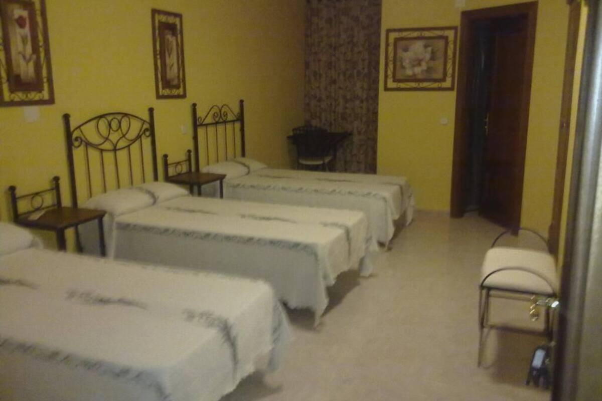 A room with three beds, a chair, and a small table.