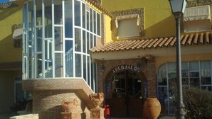 Un edificio con fachada amarilla, ventana de esquina de vidrio y un letrero que dice "ARCOJALON".