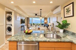 A modern kitchen with a granite countertop, a built-in dishwasher, and a fruit bowl.