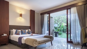 Ein Schlafzimmer mit einem großen Bett, Nachttischen, einer Bank und Blick auf einen Garten durch eine Glasschiebetür.
