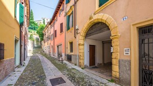 A narrow cobblestone street flanked by historic buildings with stone arches and traditional shutters.