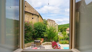 Blick aus einem Fenster auf ein Steingebäude mit Garten und Schwimmbad.