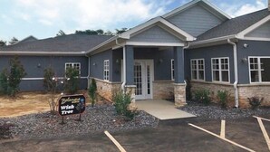 A building with a stone facade, a covered entrance, and a parking lot. - Belamere Swimming Pool Suites (Cumming)