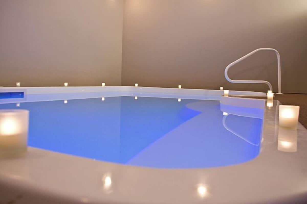 Une piscine avec un bord blanc et un intérieur bleu. Des bougies sont disposées tout autour de la piscine.