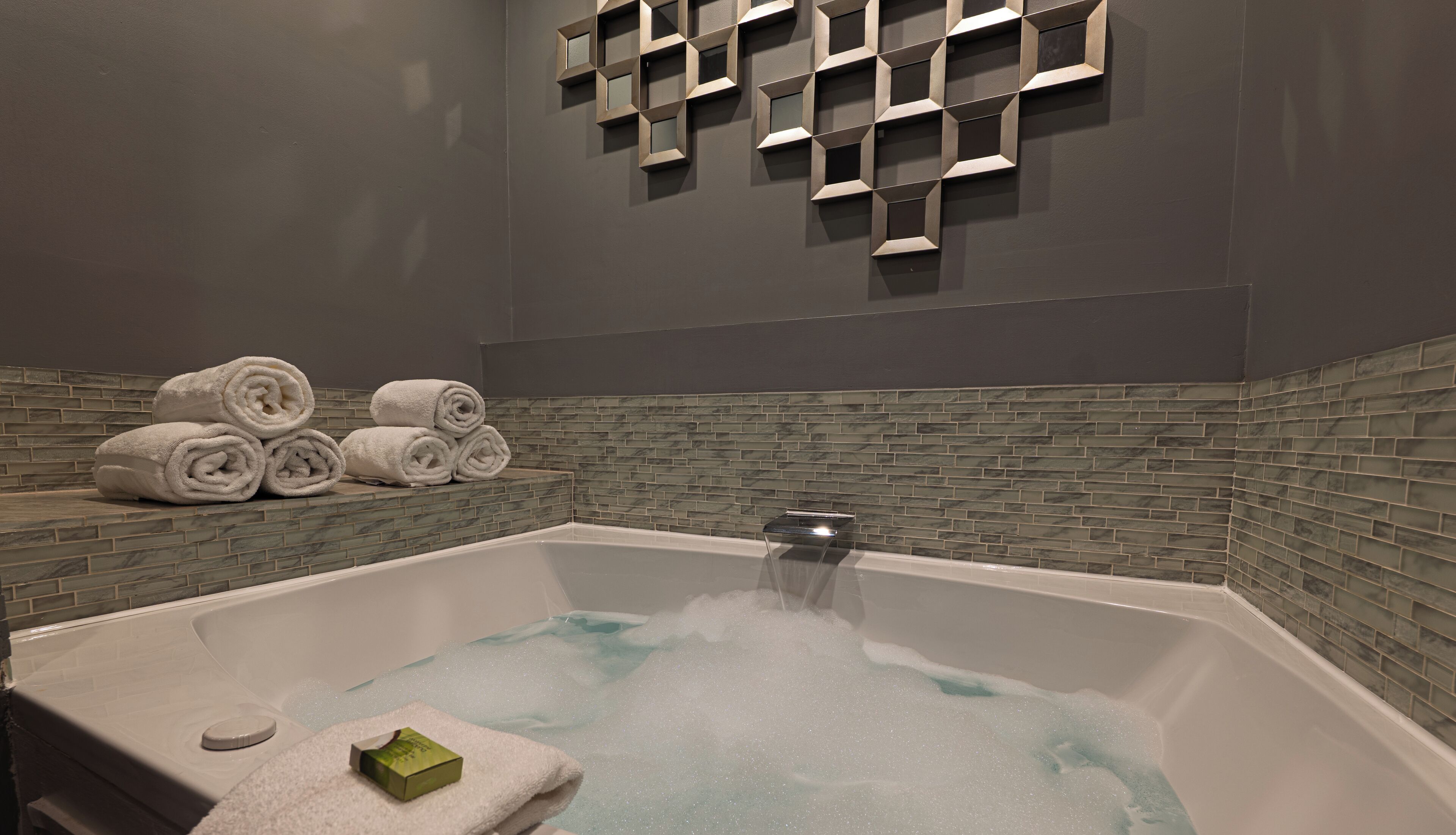 A modern bathroom with a freestanding bathtub, a tiled shower area, and neatly stacked towels.
