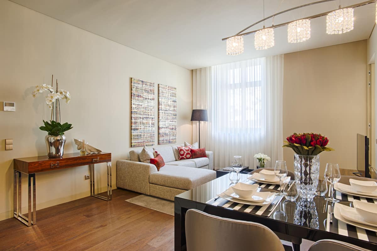 Ein modernes Wohnzimmer mit einer Couch, einem Esstisch für zwei Personen und einer Vase mit Blumen.