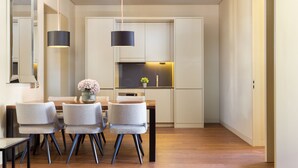 A modern kitchen with white cabinets, a dining area with a wooden table and chairs, and pendant lighting. - Lisbon Finestay 8 Building (Lisbon)