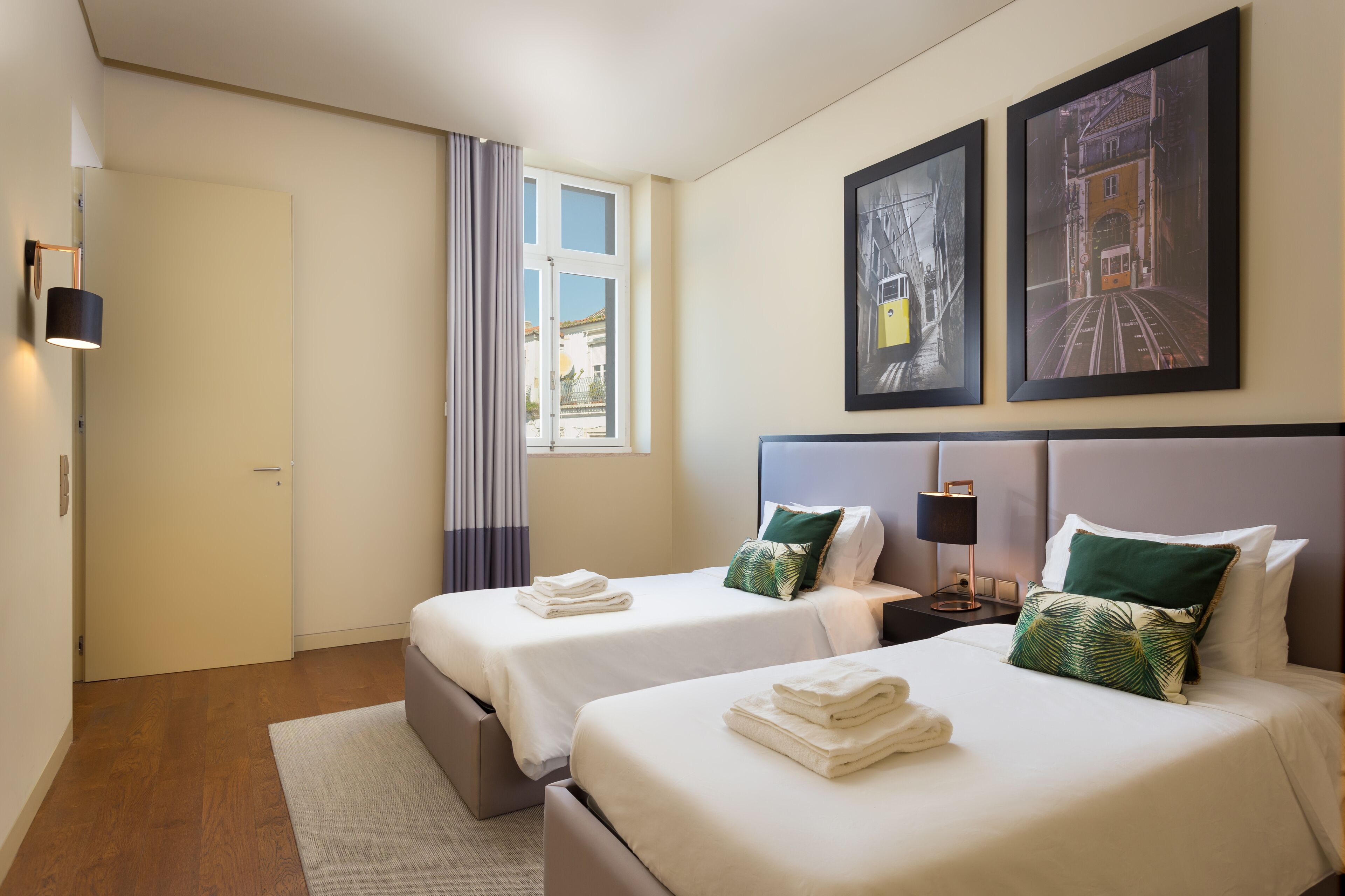 Ein Hotelzimmer mit zwei Betten, einem Fenster mit Vorhängen und Bildern an der Wand.