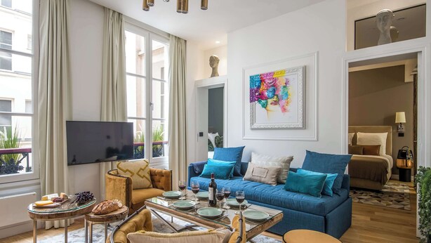 A modern living room with a blue sofa, a glass coffee table, and a television. - My Opera de Paris II (Paris)