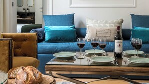 A cozy living room with a blue sofa, a wooden coffee table set with plates and wine glasses, and a brown armchair. - My Opera de Paris II (Paris)