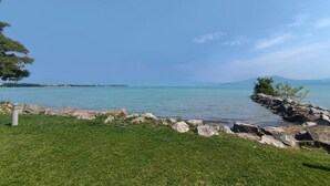 A grassy area with a rocky shoreline and a clear view of the sea.