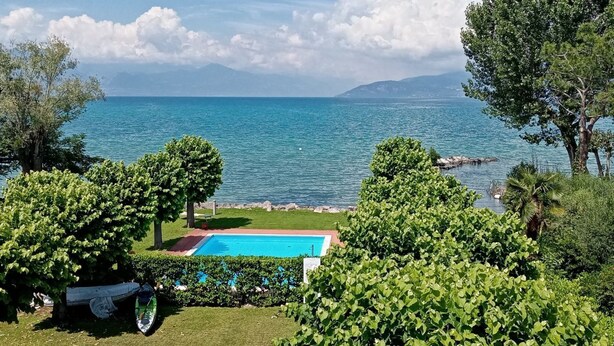 A pool with a clear view of the sea and mountains in the background.