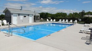 En swimmingpool med liggestole og en mindre bygning, sandsynligvis omklædningsrum eller opbevaring.
