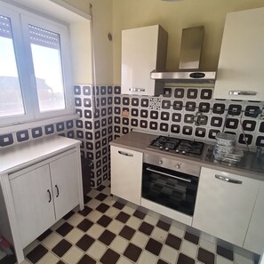 A kitchen with a gas stove, oven, and white cabinets. - The beach is 20 meters away (Tarquinia Lido)