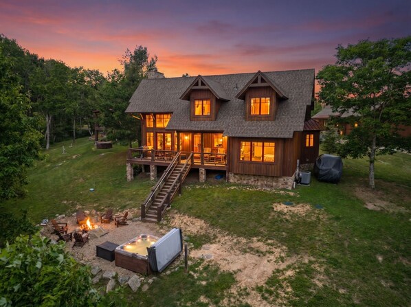 A large house with a deck, a hot tub, and a fire pit.