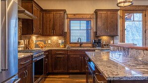 A modern kitchen with dark wood cabinets, stainless steel appliances, and granite countertops.