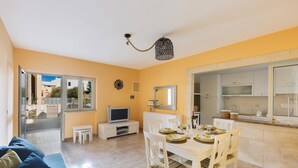 A compact living space with a dining area, kitchenette, and a TV.