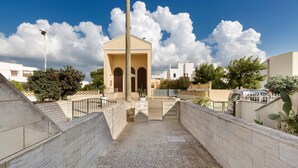 A courtyard with a central building, a paved area, and a gated entrance.