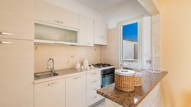 A modern kitchen with light-colored cabinets, stainless steel appliances, and a granite countertop.
