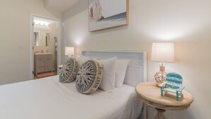 Un dormitorio con cama, dos relojes de pared, un cuadro, una lámpara y una pequeña mesa con una silla.
