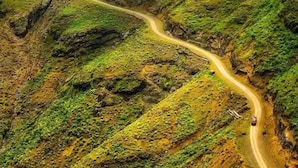 Una carretera sinuosa atraviesa un paisaje montañoso de abundante vegetación.
