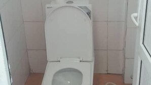 Un baño pequeño con azulejos, un inodoro blanco y un rollo de papel higiénico a la vista.