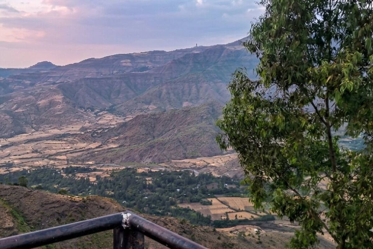 A mountainous landscape with a valley and a distant mountain range.