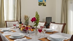 A dining table set with plates, glasses, and a fruit bowl. - Luxury new villa on mountainside with private swimming pool & garden (Kathikas)
