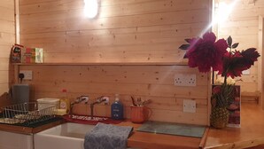 Interior de una cabaña de madera con un lavamanos, artículos de aseo y una piña en la encimera.