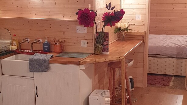 Interior acogedor de una cabaña con paredes de madera, una cocina, una mesa de comedor y una zona de descanso.