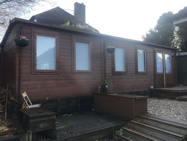 Una cabaña de madera con cuatro ventanas, un porche pequeño y una chimenea.