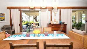 A dining area with a wooden table, wicker chairs, and hanging pendant lights.