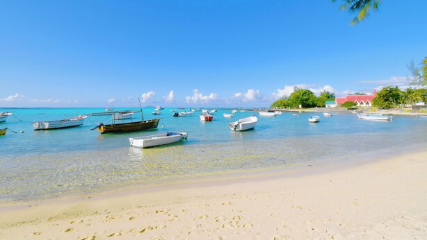 A beach with several boats anchored in the water and a sandy shore.