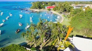 A coastal area with numerous boats docked in clear blue waters, surrounded by lush greenery and a few buildings.