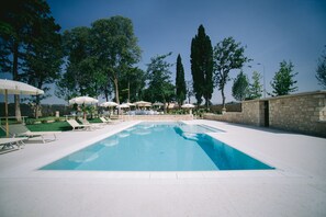 A swimming pool with lounge chairs and umbrellas, surrounded by trees and stone walls. - Boutique Hotel Villa Zoppi - Adults Only (Colognola ai Colli)