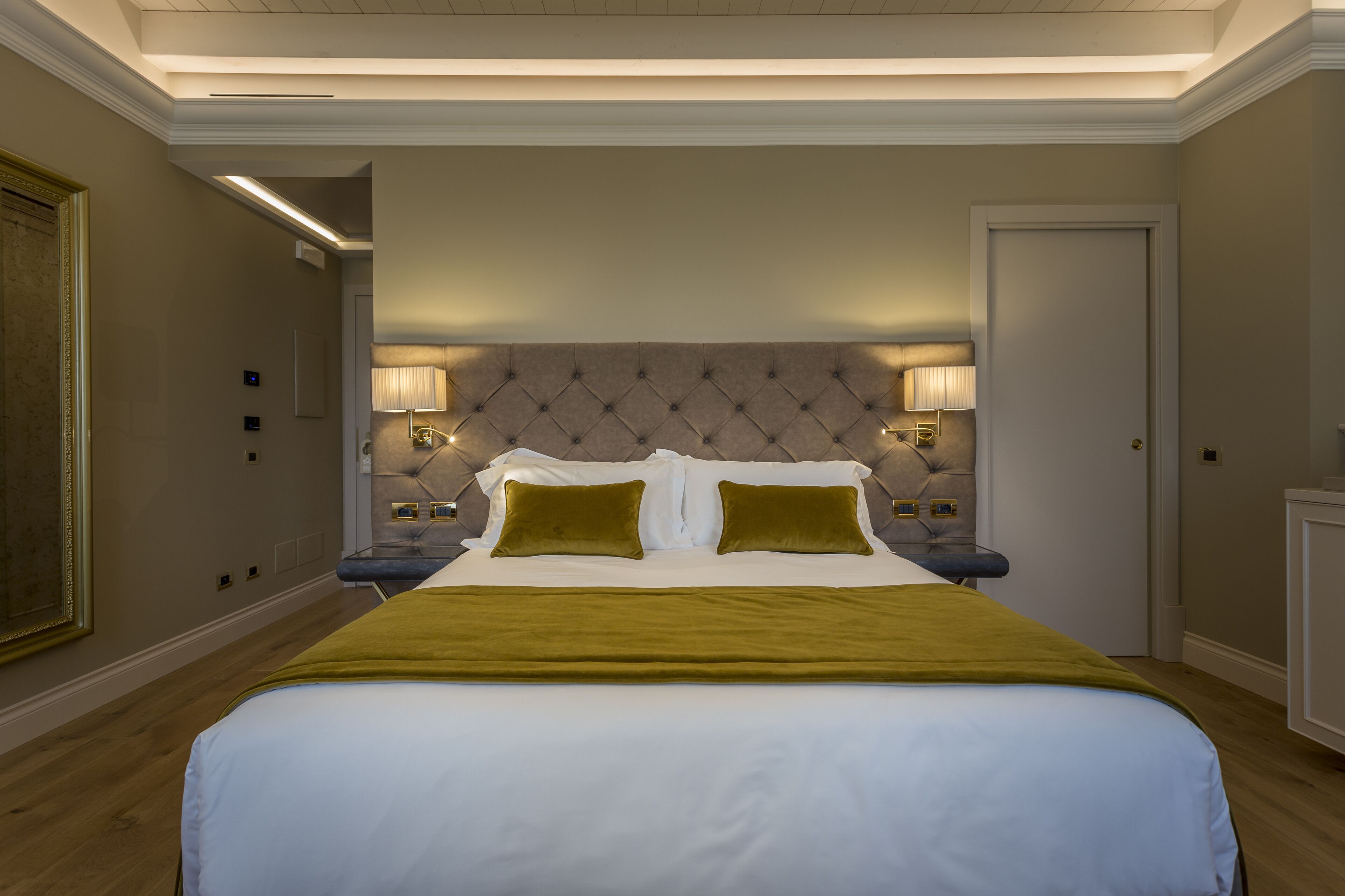 A neatly arranged hotel room with a large bed, two bedside lamps, and a framed picture on the wall.