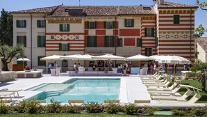 A hotel with a swimming pool, outdoor seating, and a terrace.