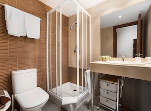 Enjoy a refreshing shower in the walk-in shower with clear glass doors, a white toilet, and a vanity with a large mirror.
