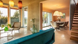 A modern living room with a sofa, a coffee table, and a dining area with chairs and a table. - Villa Luxi private pool, jacuzzi, housekeeping and concierge (Is Molas)
