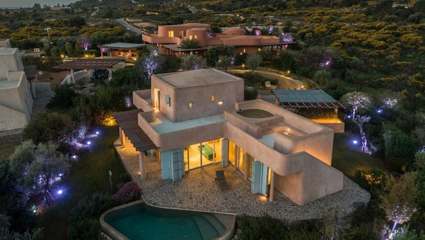 A modern, multi-story villa with a pool, surrounded by landscaped gardens and a mountainous backdrop. - Villa Luxi private pool, jacuzzi, housekeeping and concierge (Is Molas)